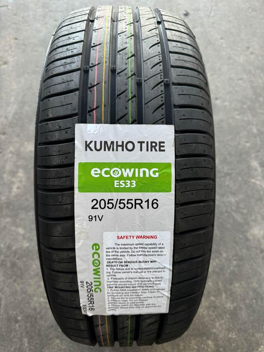 A new Kumho ES33 Ecowing tire with labeling indicating the size and model, placed on a grey surface.