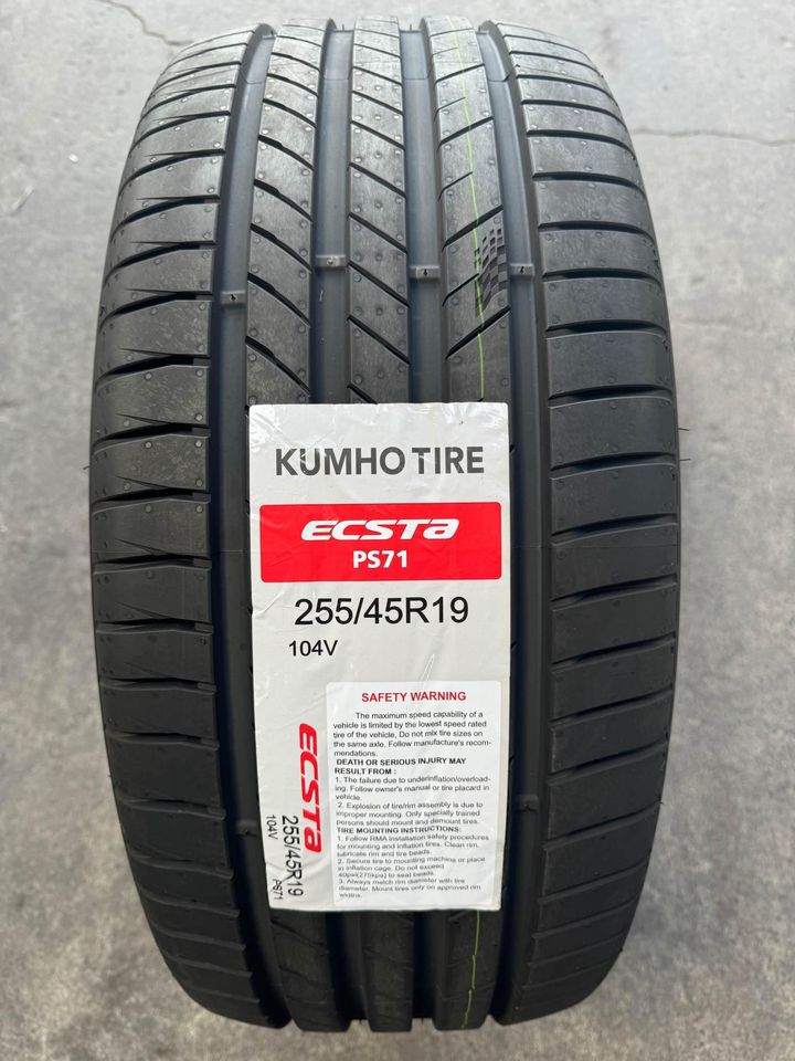 A black KUMHO ECSTA PS71 tire positioned upright, featuring product labels and tread pattern visible.