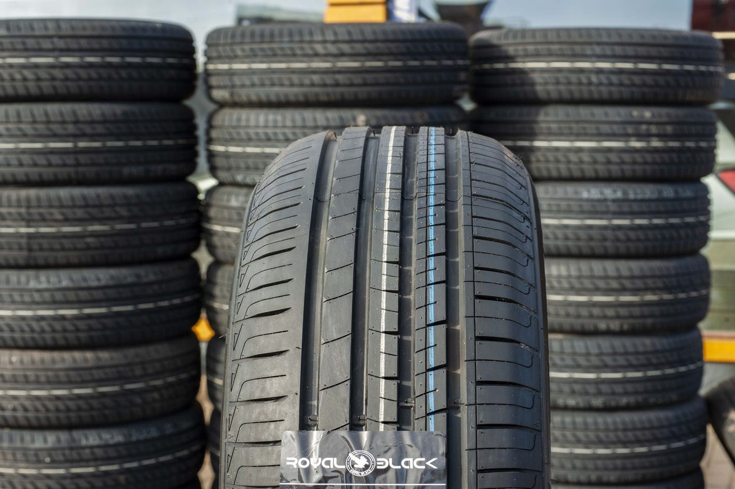 Stacks of tires with a focus on one tire displaying 'Royal Black' branding.