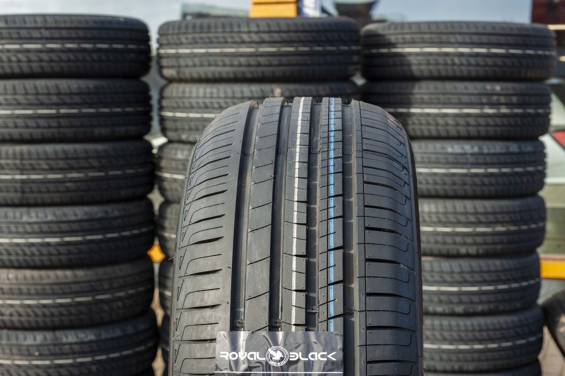 Stacks of tires with a focus on one tire displaying 'Royal Black' branding.